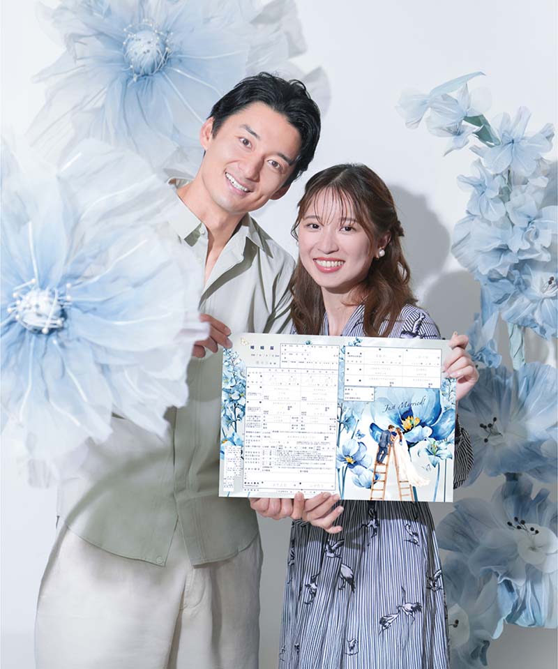 お洒落なジャイアントフラワーがあるスタジオで撮影した、婚姻届を持つカップルの入籍フォト
