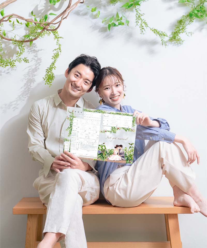 爽やかなボタニカル背景のスタジオで撮影した、婚姻届を持つカップルの入籍フォト